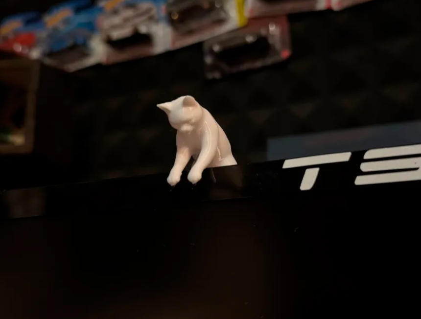 3D-printed cat peeking over the top of a monitor