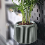 3D-printed fluted pegboard planter with a small plant