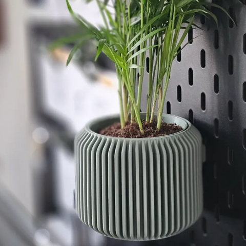 3D-printed fluted pegboard planter with a small plant
