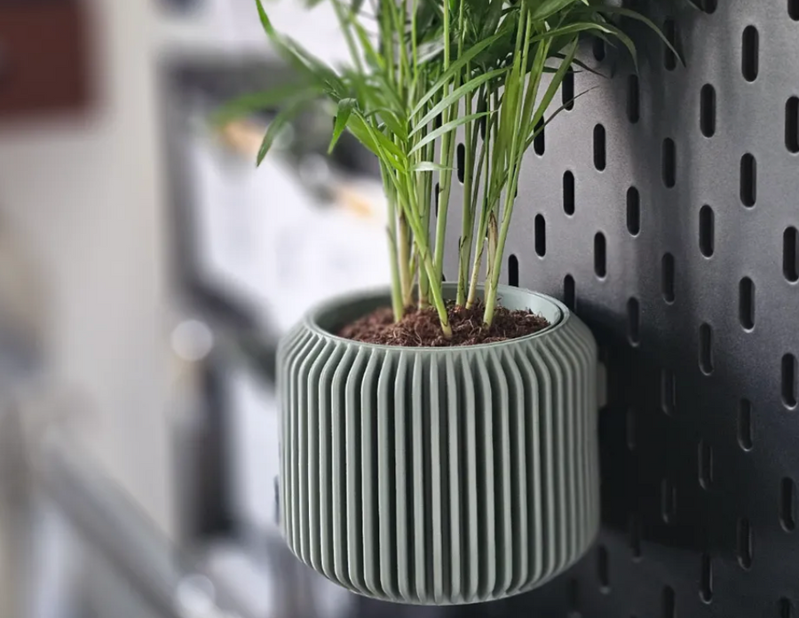 3D-printed fluted pegboard planter with a small plant