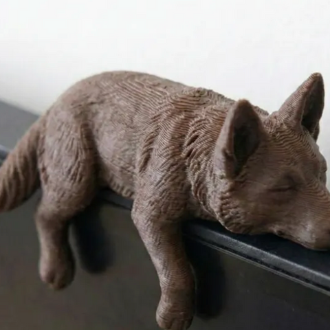 Sleeping wolf 3D print resting on a monitor edge