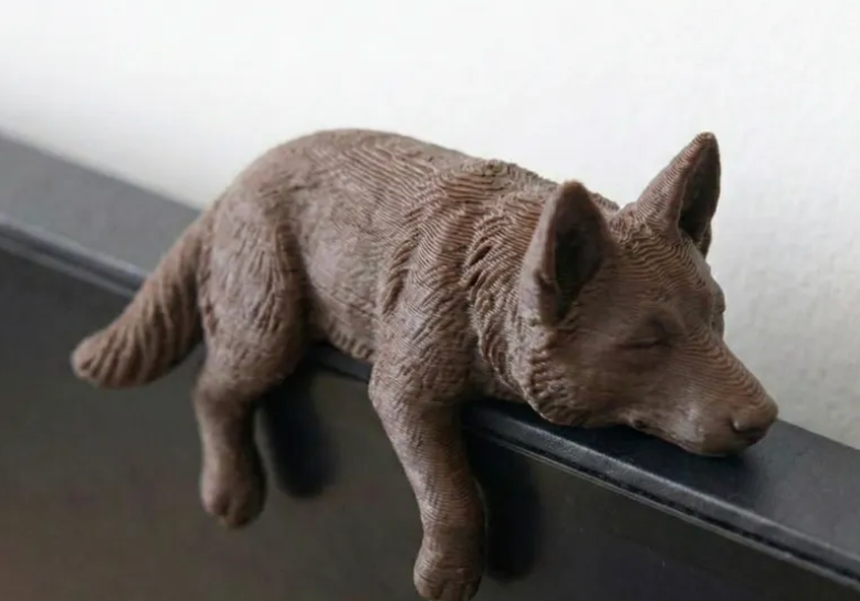 Sleeping wolf 3D print resting on a monitor edge
